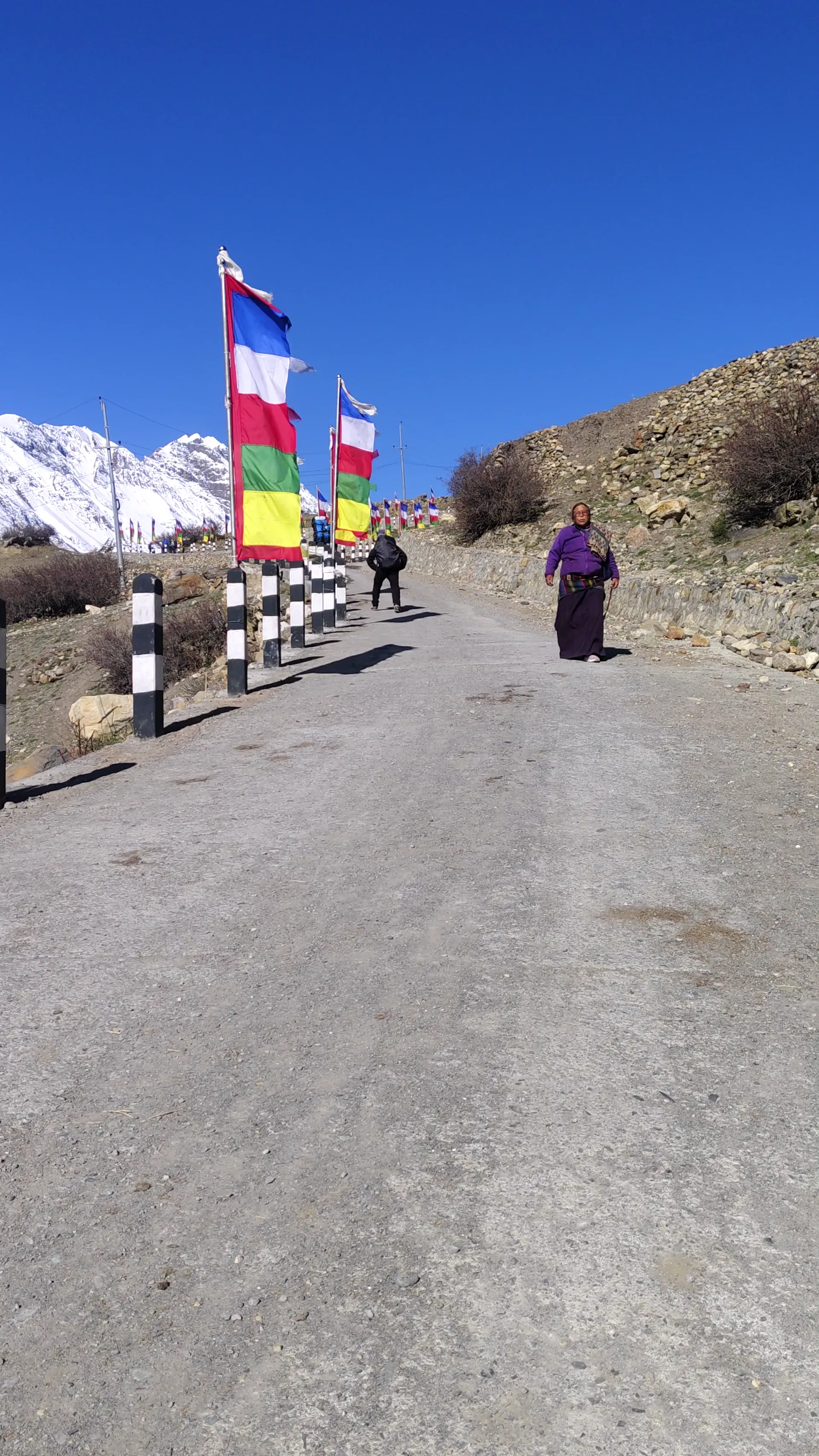 Local woman and trekker on a road lined with colorful prayer flags