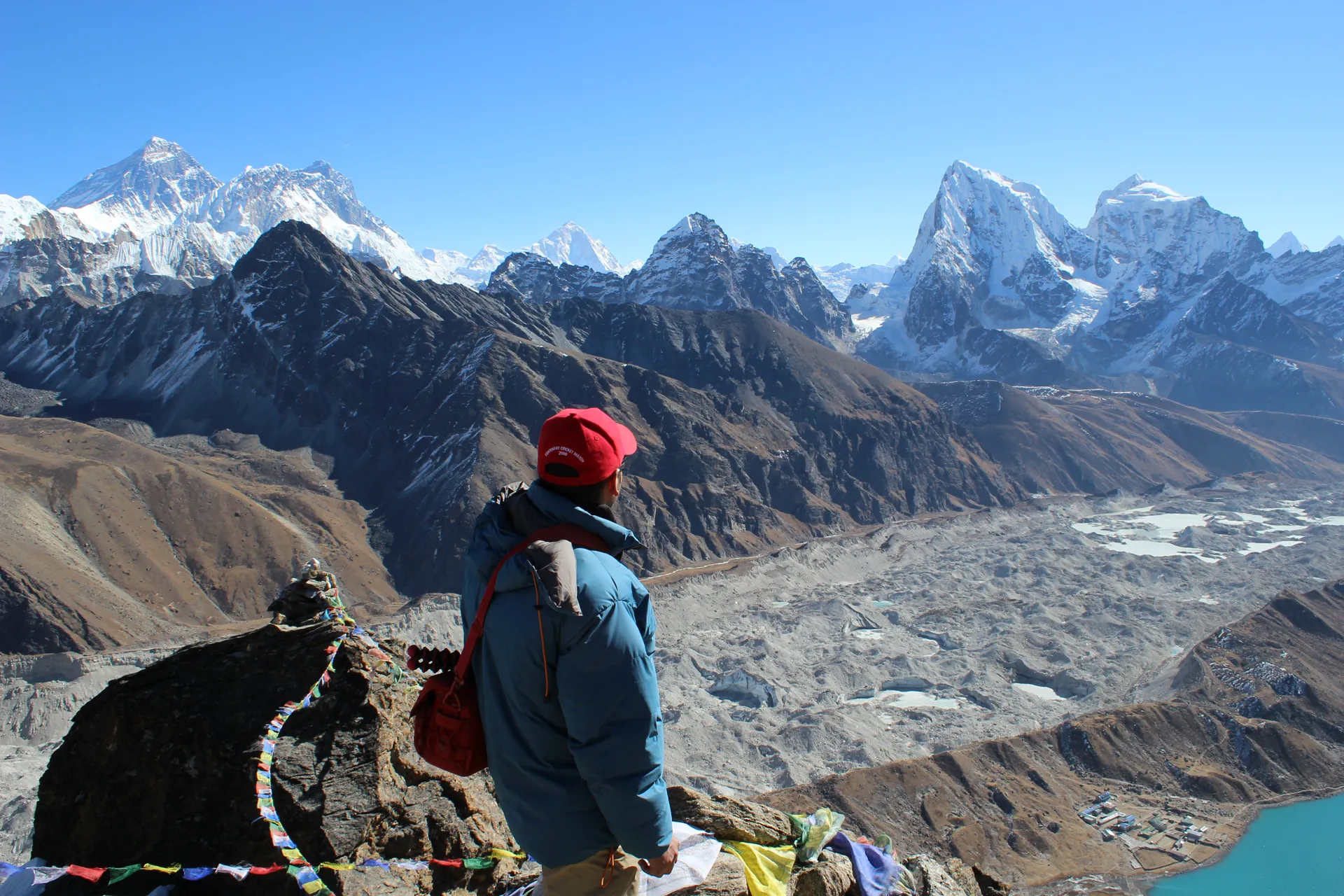 Trekker in red hat viewing Ngozumpa Glacier and Everest range from Gokyo Ri