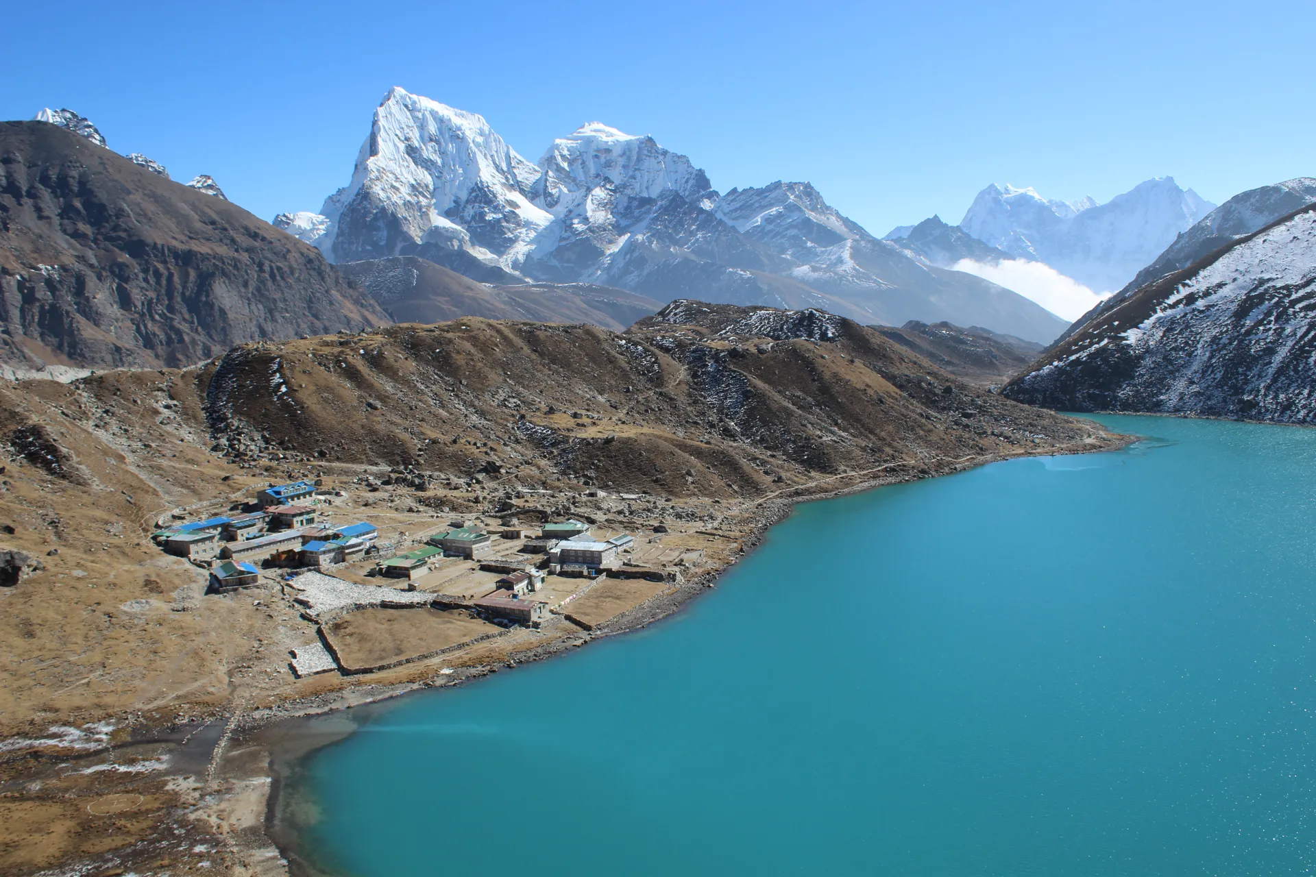Gokyo village with blue-roofed lodges on the shore of turquoise Gokyo Lake