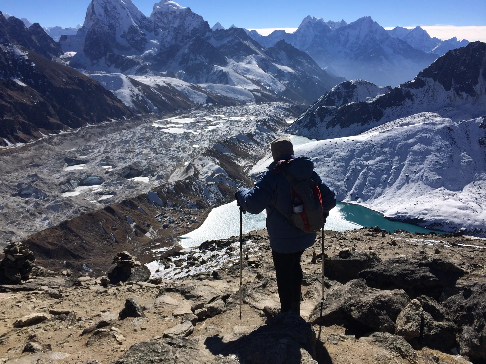 Solo trekker overlooking Ngozumpa Glacier and a turquoise glacial lake