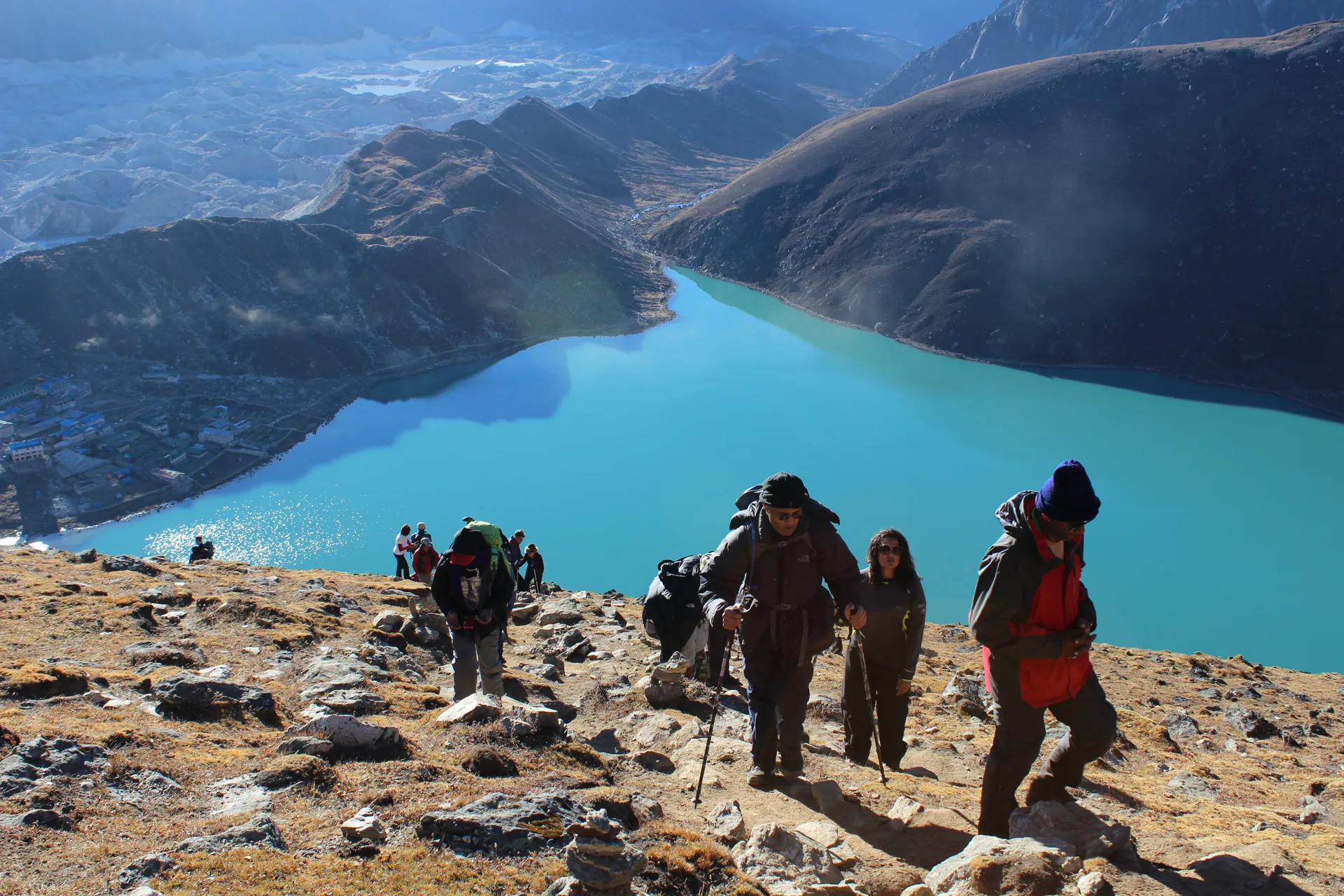 Trekking group climbing steep slope above turquoise Gokyo Lake