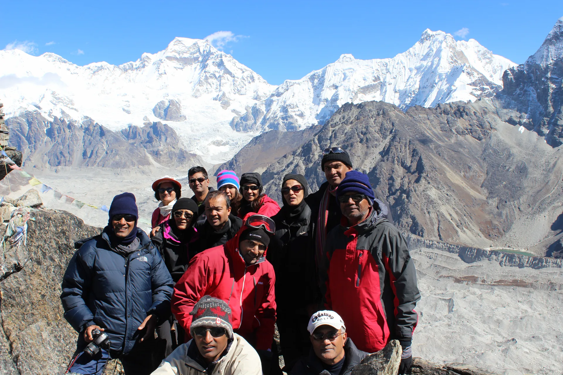Trekking group of twelve at Gokyo Ri summit with Cho Oyu and prayer flags