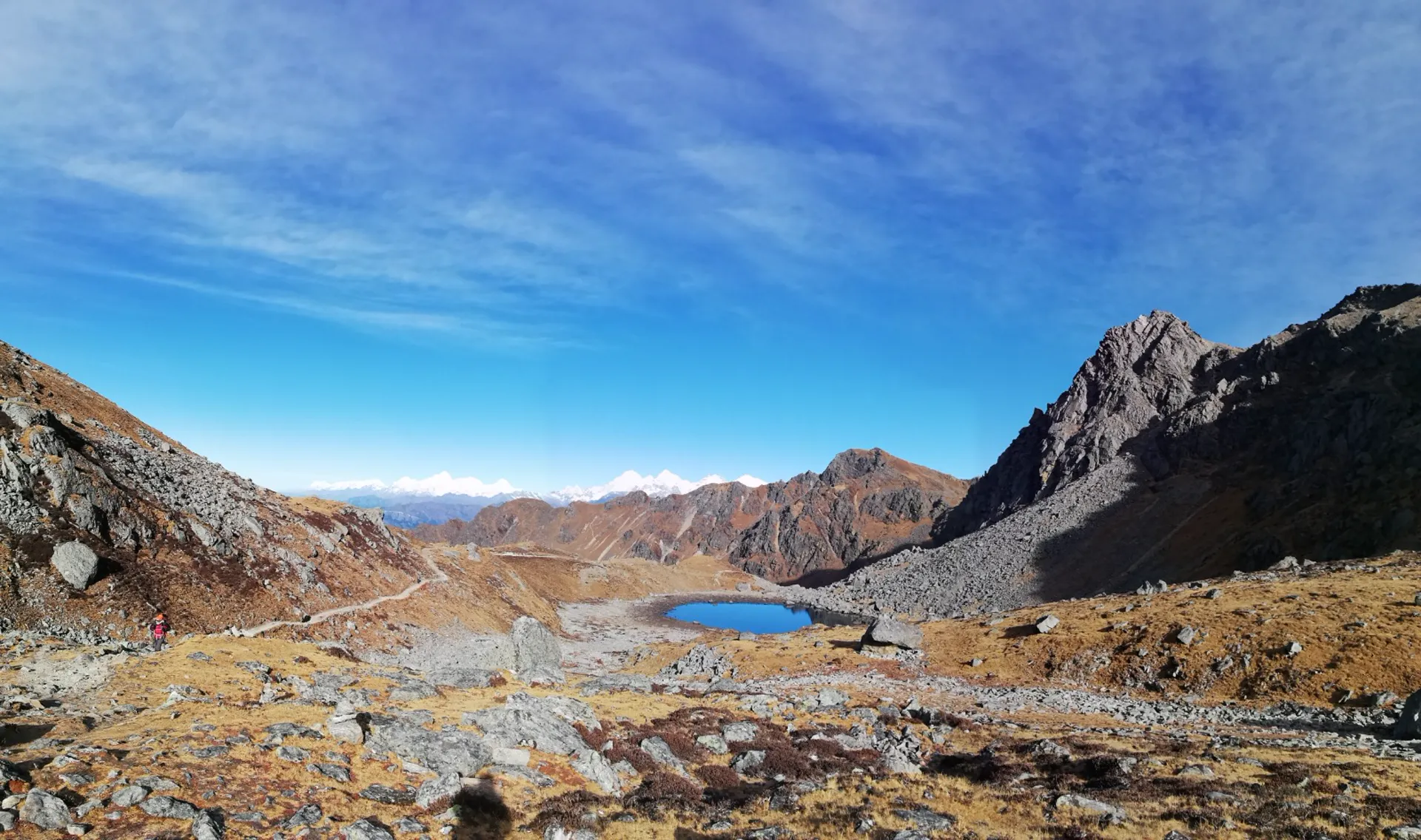 Distant alpine lake nestled in a rocky brown valley on the Gosaikunda trail