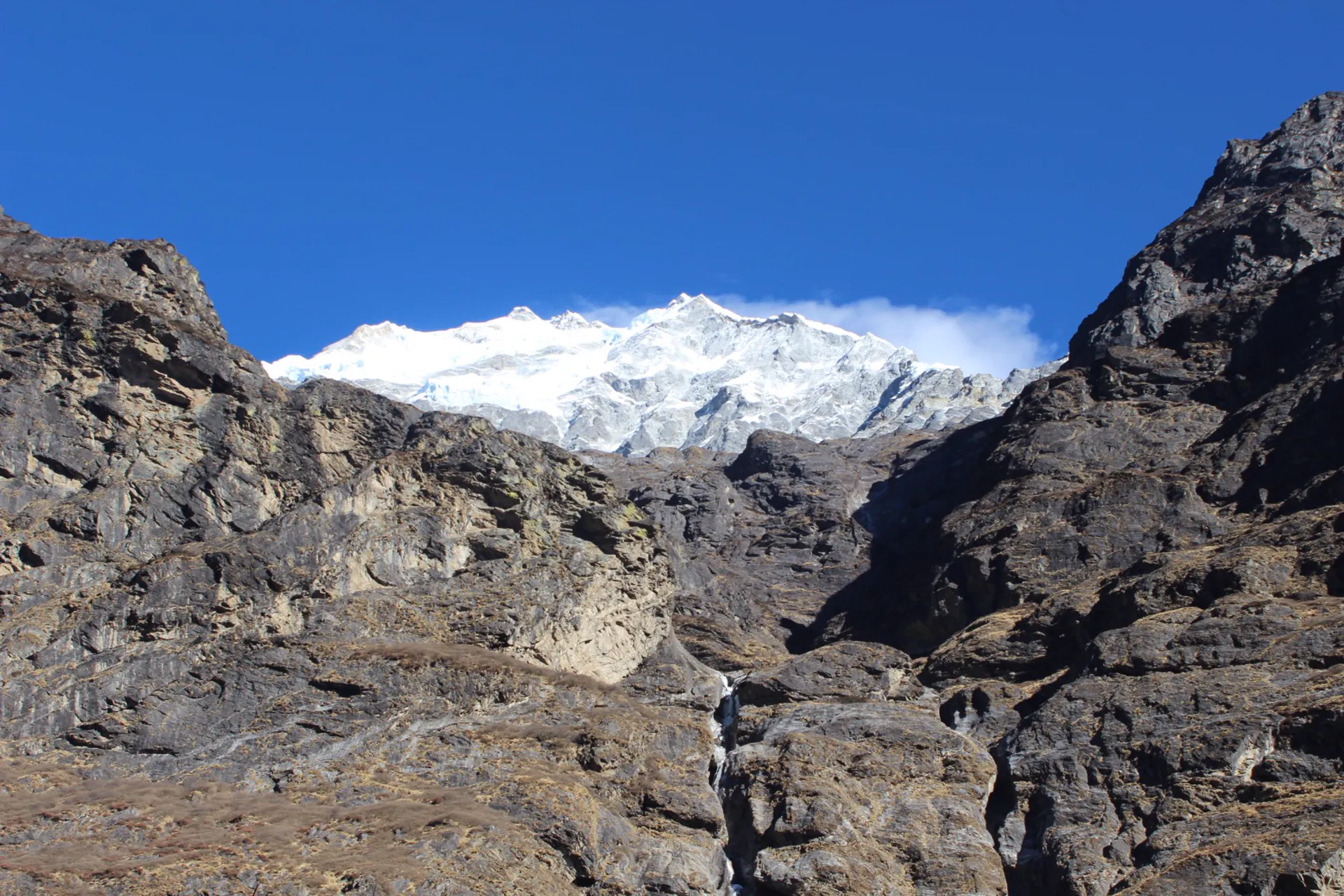 Snow-covered Langtang Lirung framed between dark rocky cliffs in a narrow valley