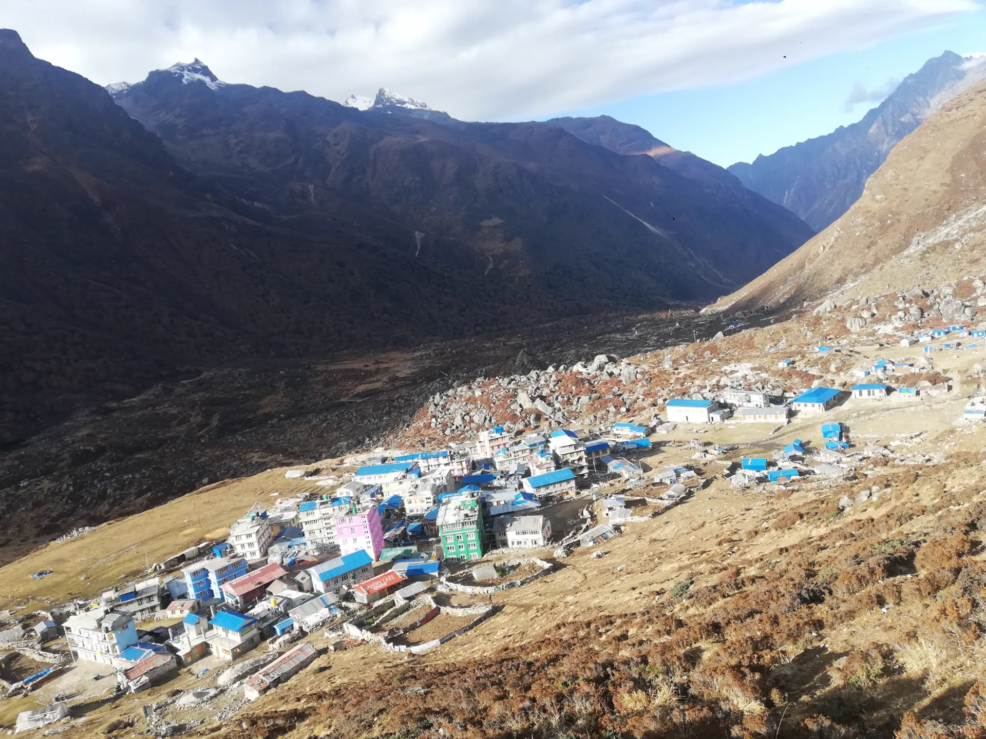 Aerial view of Langtang village rebuilt with blue and colorful roofs in a steep valley