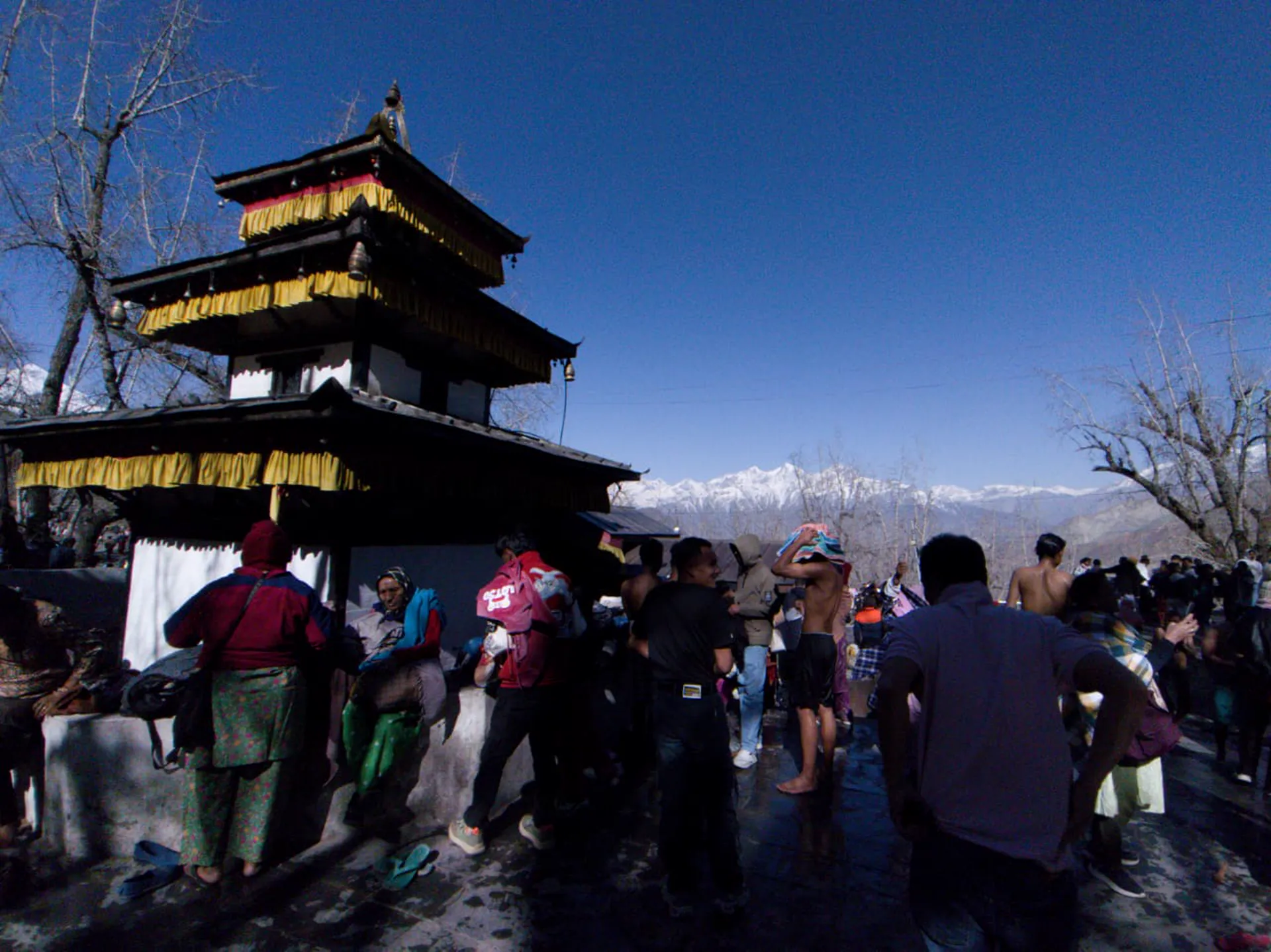 Wide view of Muktinath Temple complex with pilgrims and the Annapurna-Dhaulagiri range on the horizon