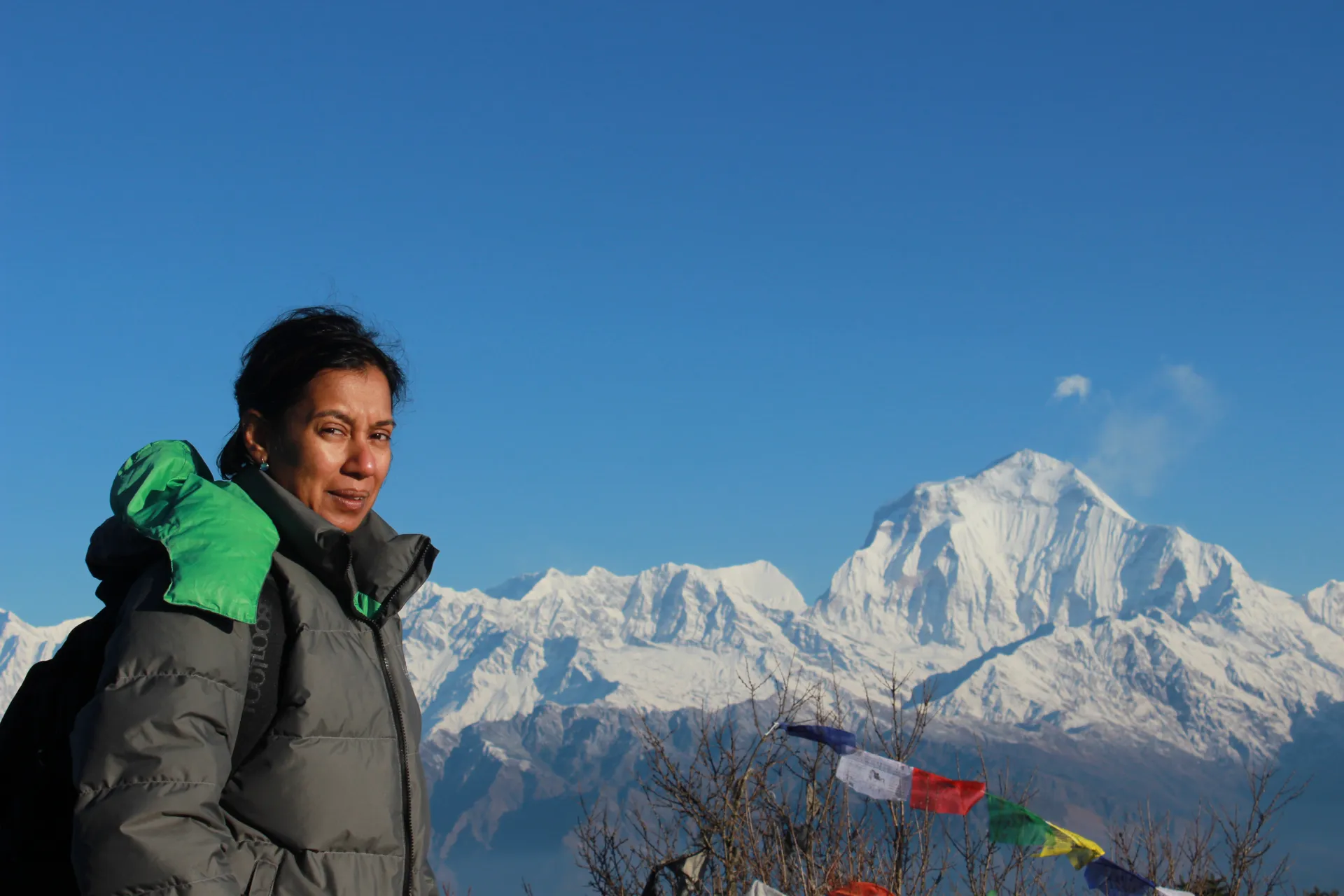 Female trekker in a down jacket at Poon Hill with Dhaulagiri behind her