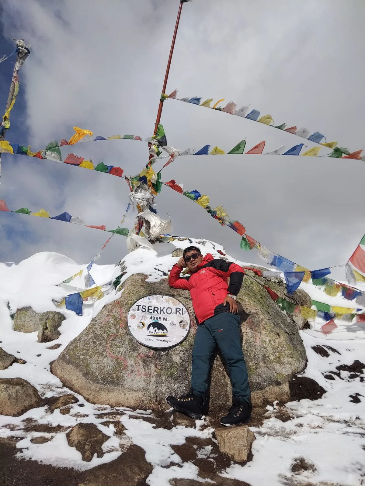 Prem at the Tserko Ri summit marker with prayer flags in Langtang